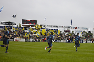 Spillerne lber p banen med flag og brndbyfans i baggrunden