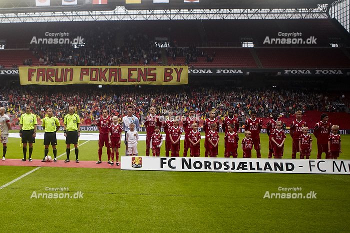 FCN-fans med banneret "Farum pokalens by" bag de to hold og dommerne